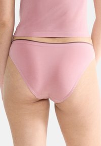 Jasnoróżowe bawełniane majtki o gładkiej fakturze, z subtelną gumką w talii i minimalnym przeszyciem dla uzyskania bezszwowego wyglądu.