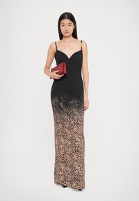 Robe noire avec un dégradé imprimé léopard, fines bretelles et décolleté plongeant. Pochette en cuir rouge à la main, design épuré.