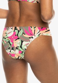 Bas de bikini multicolore présentant un motif floral en rose, vert et crème sur fond noir. Design ajusté avec des coutures sur les côtés.