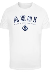 White cotton t-shirt featuring bold navy text "AHOI" with an anchor and sailor graphic, and "KNUT & JAN HAMBURG" underneath. Short sleeves.