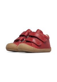 Scarpe in pelle rossa con due cinturini in Velcro, punta arrotondata e suola in gomma texturizzata color beige. Cuciture minime e dettagli di branding presenti.
