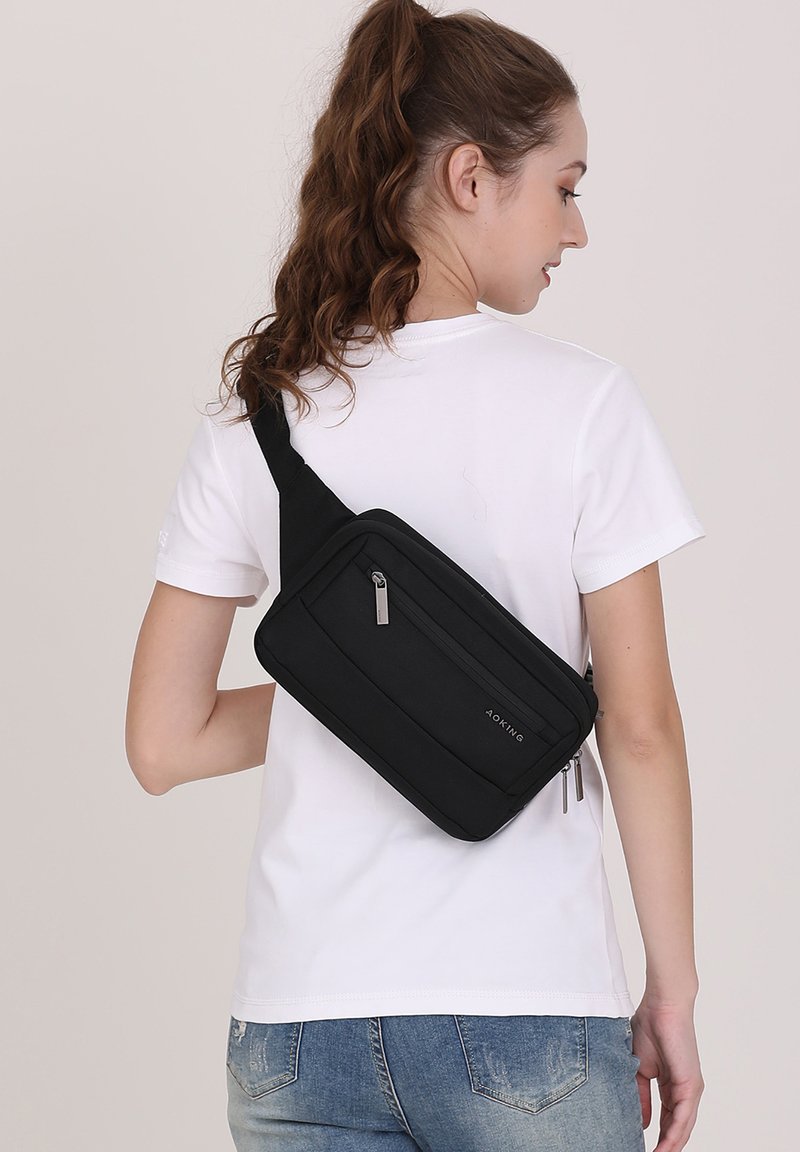 Borsa a spalla nera con forma rettangolare, dotata di più scomparti con zip e una tracolla regolabile. Tessuto testurizzato.