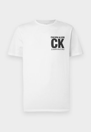 Valge puuvillane t-särk, millel on must "CALVIN KLEIN" logo ja vasakul rinnal tekst "CK Established 1968". Lühikesed varrukad, klassikaline lõige.