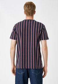 Camiseta de manga corta azul marino con rayas verticales rojas y blancas. Corte regular con cuello redondo y detalles de costura mínimos.