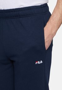 Donkerblauwe sweatpants van een zachte katoenmix, met een elastische tailleband, zijzakken en een klein geborduurd Fila-logo in rood en wit.