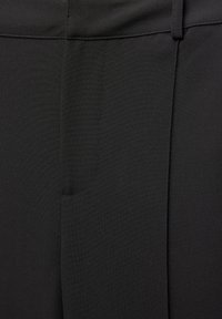 Pantalon noir au toucher lisse, doté d'une poche latérale et de coutures précises, conçu avec une silhouette épurée.