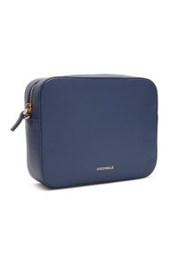 Modrá kožená obdélníková taška s texturovaným povrchem, vybavená zlatým zipem a logem na přední straně. Kompaktní design.