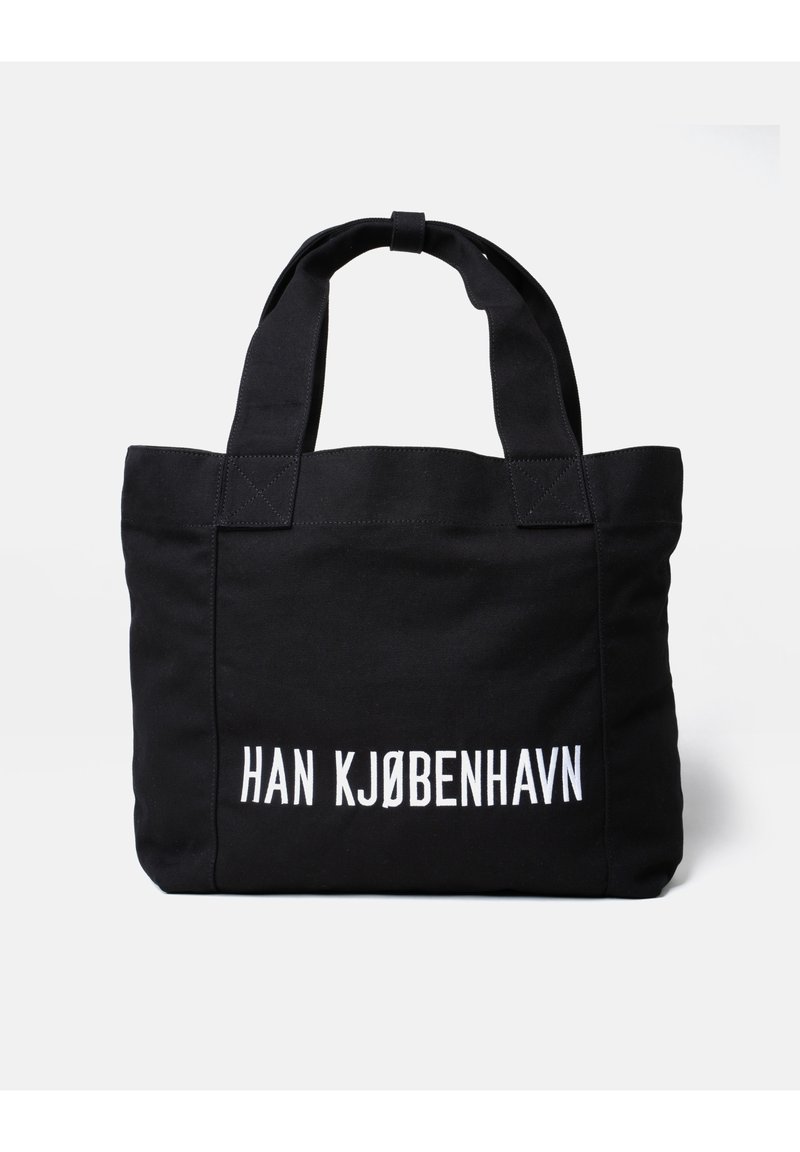 Czarna torba na ramię z dwiema rączkami, z białym napisem "HAN KJØBENHAVN" i minimalistycznym wzorem. Solidna tekstura i wyraźnie zarysowany kształt.