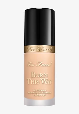 Flasche der Too Faced Born This Way Foundation mit schwarzem Verschluss, nude-farbenem Körper, goldener Schrift und weißem Sockel. Formel mit mittlerer bis voller Deckkraft.