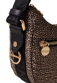 Sac à bandoulière en tissu à motifs beige et noir, avec une fermeture éclair dorée, des accents métalliques et une sangle texturée pour un transport sécurisé.