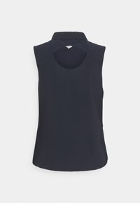 Haut noir sans manches avec un col montant et une découpe arrondie en forme de trou de serrure sous le col dans le dos.