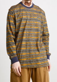 Long-sleeve shirt in gray with horizontal orange and yellow stripes. Features a navy ribbed crew neck and cuffs. Includes a logo on the chest.