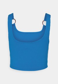 Haut court bleu côtelé avec larges bretelles et accents en anneau métallique aux épaules. Le tissu a une texture lisse et une silhouette ajustée.