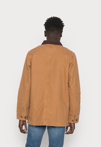 Braune Baumwolljacke mit einem Cordkragen, langen Ärmeln und Knopfärmeln, mit lässiger Passform und Rückennahtdetails.