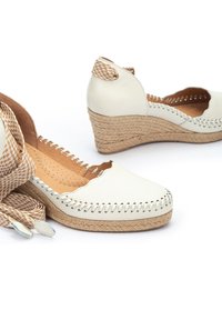 Bottines en cuir blanc avec semelle en jute tissée, bord festonné et couture décorative. Comprend une sangle tissée à motif à carreaux.