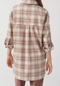 Rutigt skjorta i beige och rosa nyanser, med krage, uppvikta trekvartslånga ärmar och en bakficka för ökad rörelse. Slät tygkvalitet.