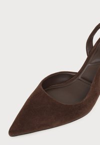 Chaussure slingback en daim marron à bout pointu, talon bas et semelle intérieure rembourrée sur fond clair.