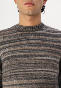Gestreepte gebreide trui met een ronde hals, in verschillende tinten bruin, grijs en beige. Zachte, gestructureerde wollen stof met een ontspannen pasvorm.