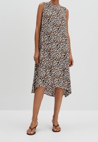 Ærmeløs kjole i et brunt, hvidt og sort blomstermønster, knælængde med en asymmetrisk kant. Letvægtsstof, flydende design.