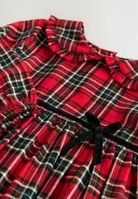 Abito a quadri rossi con colletto sbuffato, fiocco in velluto nero in vita e dettaglio in vita elasticizzato. Tessuto morbido con motivo a quadri.