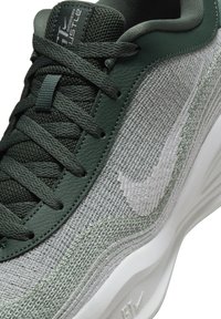 Zelené a šedé tenisky s texturovaným pleteným svrškem, koženými akcenty a bílým logem Swoosh. Obsahují ploché tkaničky a polstrovanou podrážku.