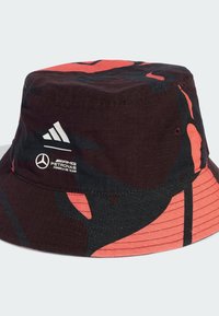 Black and red patterned bucket hat with a wide brim, featuring Adidas and Mercedes logos in white. Made from textured fabric.