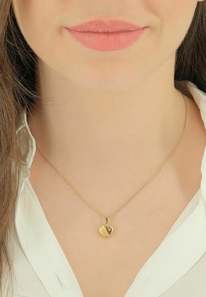 Collier pendentif cœur en or avec un petit accent en pierre, suspendu à une chaîne fine. Le pendentif présente une surface polie et texturée.