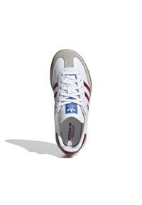 Sneaker blanche avec des rayures bordeaux et des accents en suède beige. Caractéristiques : languette en maille, lacets ronds et semelle en caoutchouc. Logo bleu sur la languette.