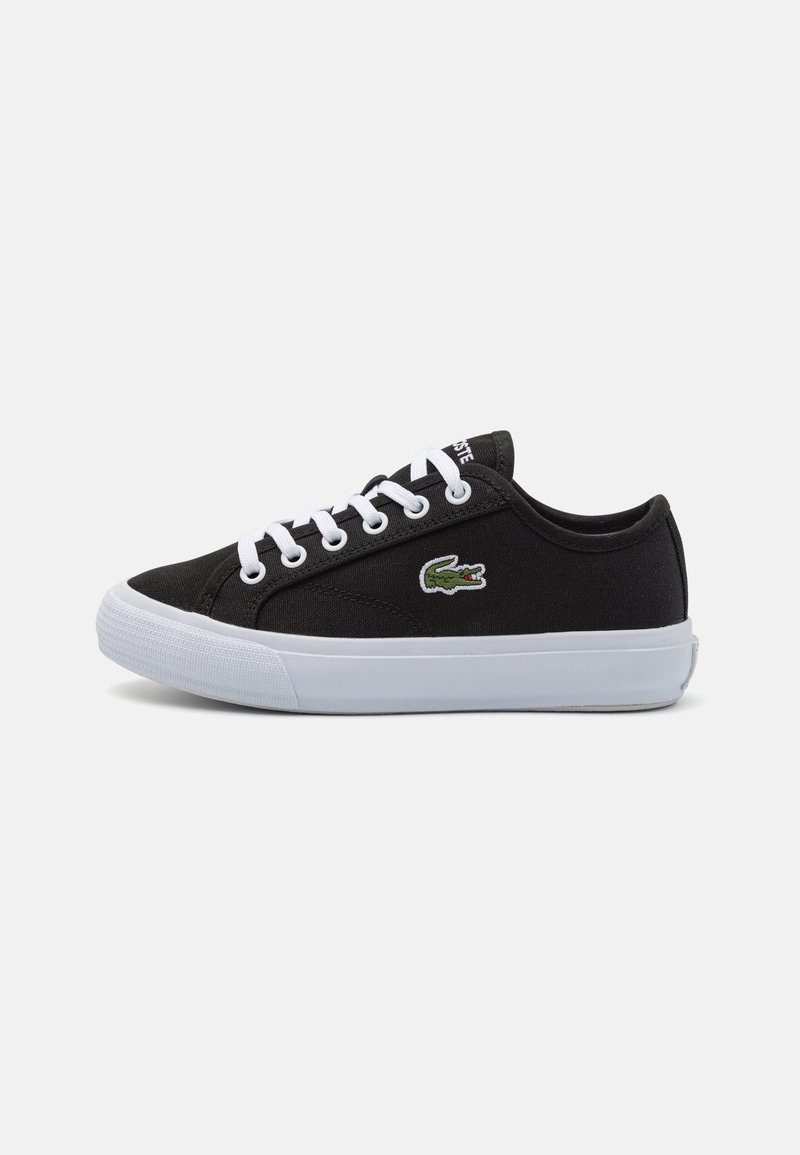 Baskets basses en toile noire avec lacets blancs, semelle blanche et logo crocodile vert sur le côté.