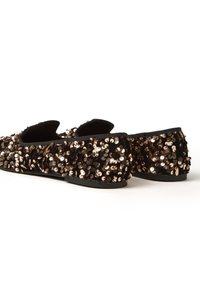 Mocasines negros adornados con lentejuelas de oro rosa, presentan una parte superior suave, punta redonda y suela plana. El tacón es bajo y facilita el uso cómodo.