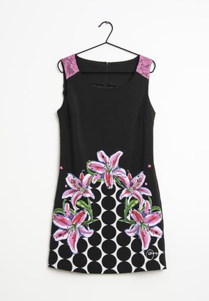 Robe noire sans manches avec bretelles en dentelle rose. Présente un motif floral coloré avec des lys roses et un motif circulaire noir et blanc à l'ourlet.