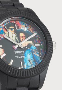 Black rubber watch featuring a colorful graphic dial with two figures, silver hour markers, and a textured bezel. Brand name "TVBOY TIMEX" displayed.
