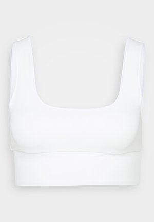 Bela brezšivna športna modrčka z širokimi naramnicami in kvadratnim izrezom, prikazana na nevtralni svetlo sivi ozadju.