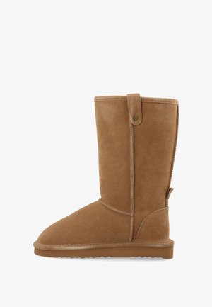 Mellanhög beige mockaboot med platt sula, rund tå, sömnadsdetaljer och dragremmar upptill och baktill.