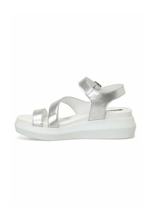Srebrni metalni sandal s nastavljivimi trakovi, v obliki peščene ure in belo podplat. Gladka tekstura z minimalističnimi oblikovalskimi podrobnostmi.