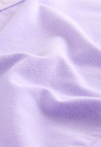 Mäkká, svetlofialová látka s jemnými záhybmi a hladkou, jemne pletenou textúrou.