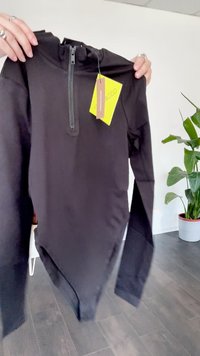 Fekete, hosszú ujjú testcorsó, magas nyakkal és cipzár részletekkel. Simá, rugalmas anyagból készült. Tartalmaz egy sárga címkét.