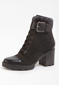 Bottine noire avec un dessus en daim présentant des détails perforés, un bout en cuir brillant et un talon épais. Comprend une accentuation par boucle.