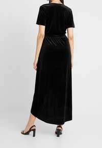 Schwarzes Samt-Maxikleid mit lockerer Passform, kurzen Ärmeln und elastischem Bund. Es hat eine glatte Textur und eine fließende Silhouette.