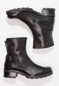 Svarta läderankelstövlar med en tjock klack, sidogömma, remdetalj och texturerad sula, som visar upp en slät yta och robust design.