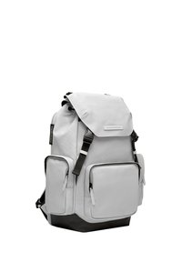 Sac à dos en tissu gris avec fermeture roulée, plusieurs poches zippées, accents noirs à la base et bretelles réglables.