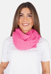 Écharpe infinie tissée rose avec une finition texturée, ornée de bords effilochés, drapée autour du cou d'un mannequin portant une chemise blanche.