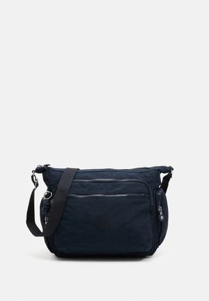 Navy crossbody bag made of textured fabric, featuring two zippered front pockets, adjustable strap, and logo accent on the side.