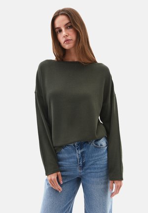 Maglietta a maniche lunghe verde scuro con vestibilità ampia, scollatura rotonda e texture morbida, abbinata a jeans in denim azzurro chiaro a vita alta.