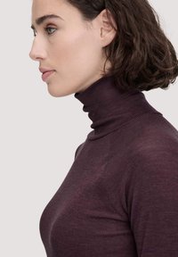 Langarmoberteil aus dunkelpflaumenfarbenem Rippstrick mit hohem Rollkragen. Verfügt über eine figurbetonte Silhouette und strukturierten Stoff.