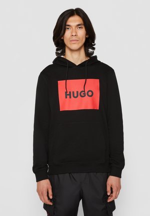 Felpa nera con cappuccio caratterizzata da una grafica rettangolare rossa con la scritta "HUGO" in grassetto nero. Presenta una tasca frontale e un cappuccio regolabile.