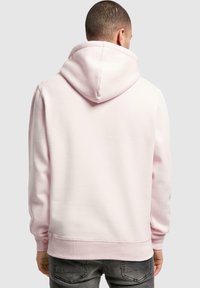 Light pink hooded sweatshirt with a soft texture, ribbed cuffs, and hem. Features a large back hood for warmth and casual design.
