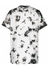 T-shirt blanc à manches courtes avec un motif tie-dye noir comportant des éclaboussures et des traînées irrégulières sur le tissu.