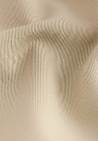 Tessuto beige con una fine trama a righe. Il materiale morbido presenta un leggero lucido e delicati pieghe, evidenziando la sua flessibilità e la caduta.