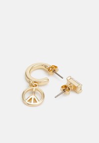 Brincos em tom dourado com design em argola, adornados com um pendente em forma de símbolo da paz e um brinco de pino. Textura suave com acabamento polido.